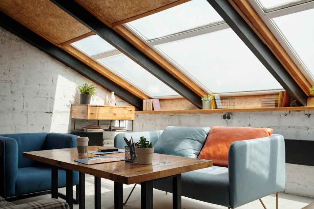 Sunlit attic study lounge with blue sofas and roof windows